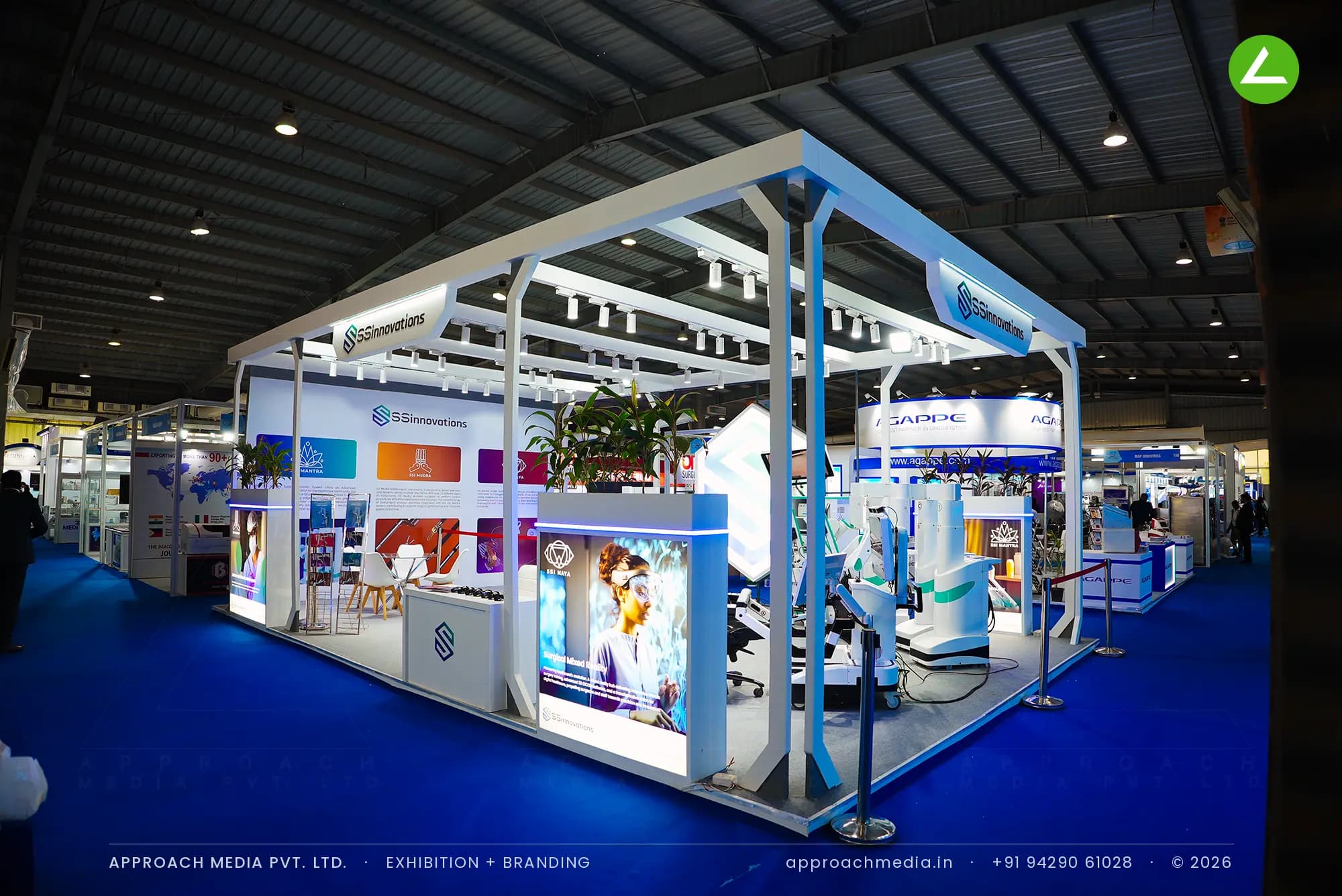 SSInnovations' white pergola stall at MedTech Expo Gandhinagar, with backlit counters ringing a live robotic surgery system