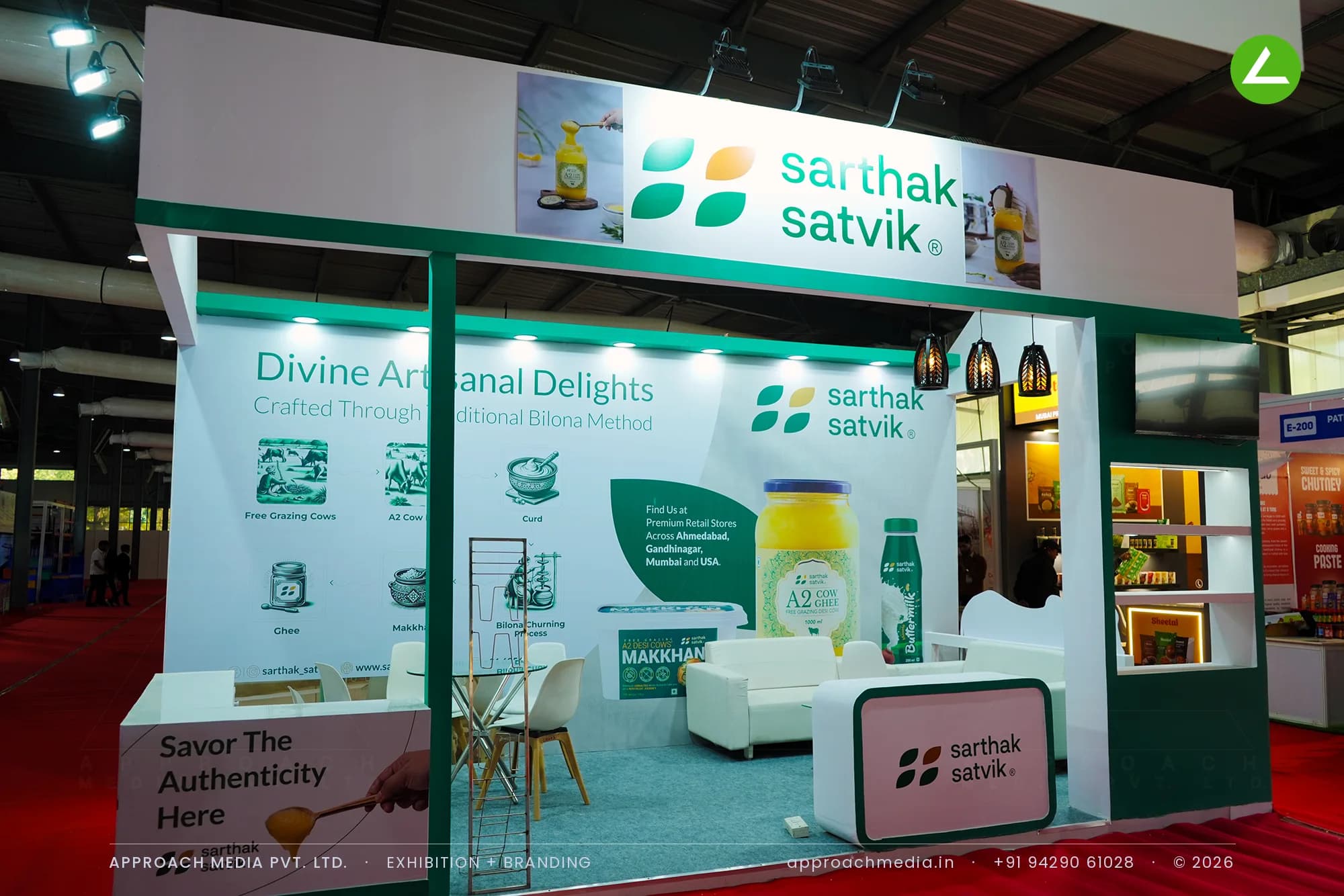 Sarthak Satvik exhibition stall design at GPBS Gandhinagar with a cream and green bilona process wall and cane pendants