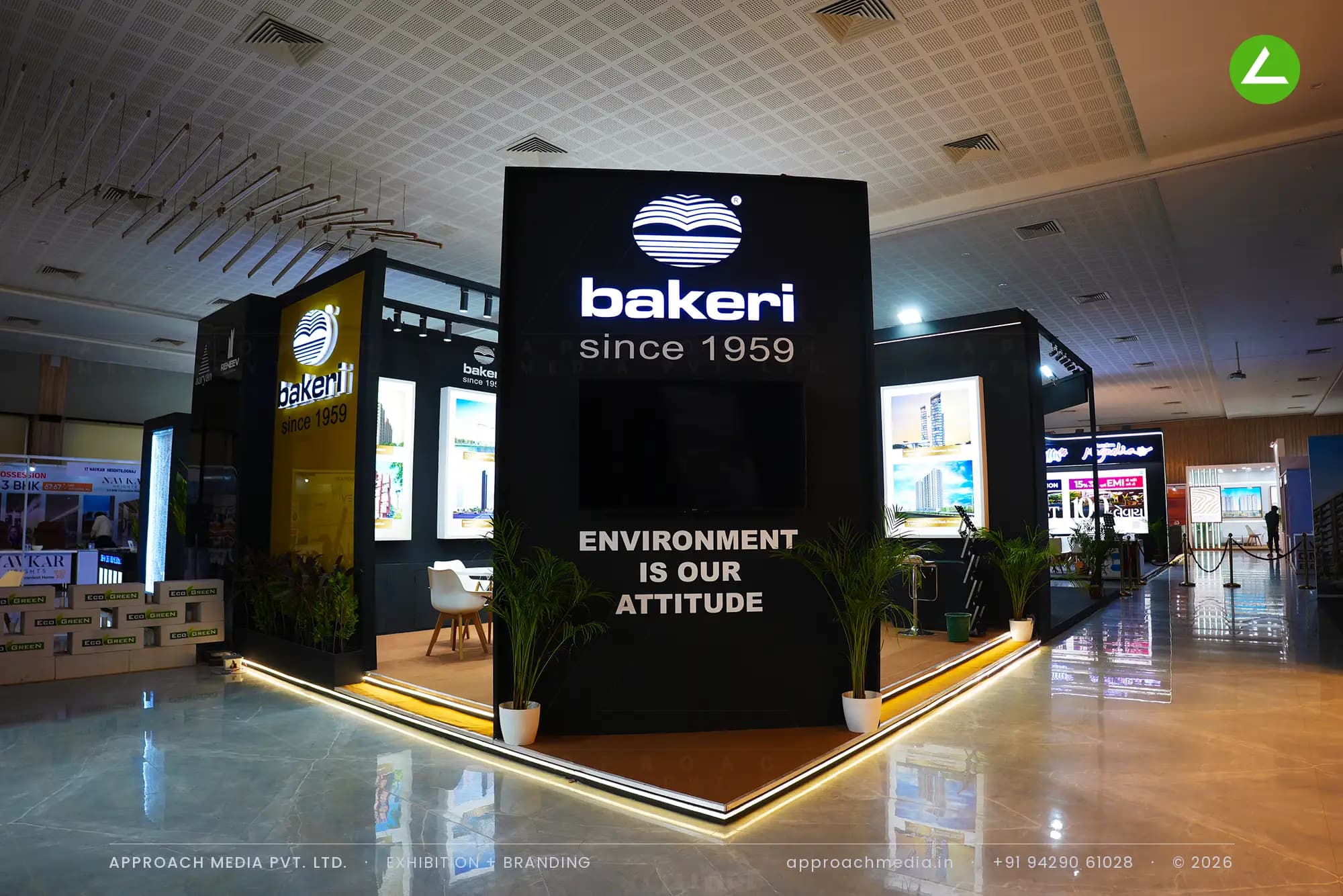 Bakeri exhibition stall design at Times Property Expo Ahmedabad with a black logo tower and edge-lit project lightboxes
