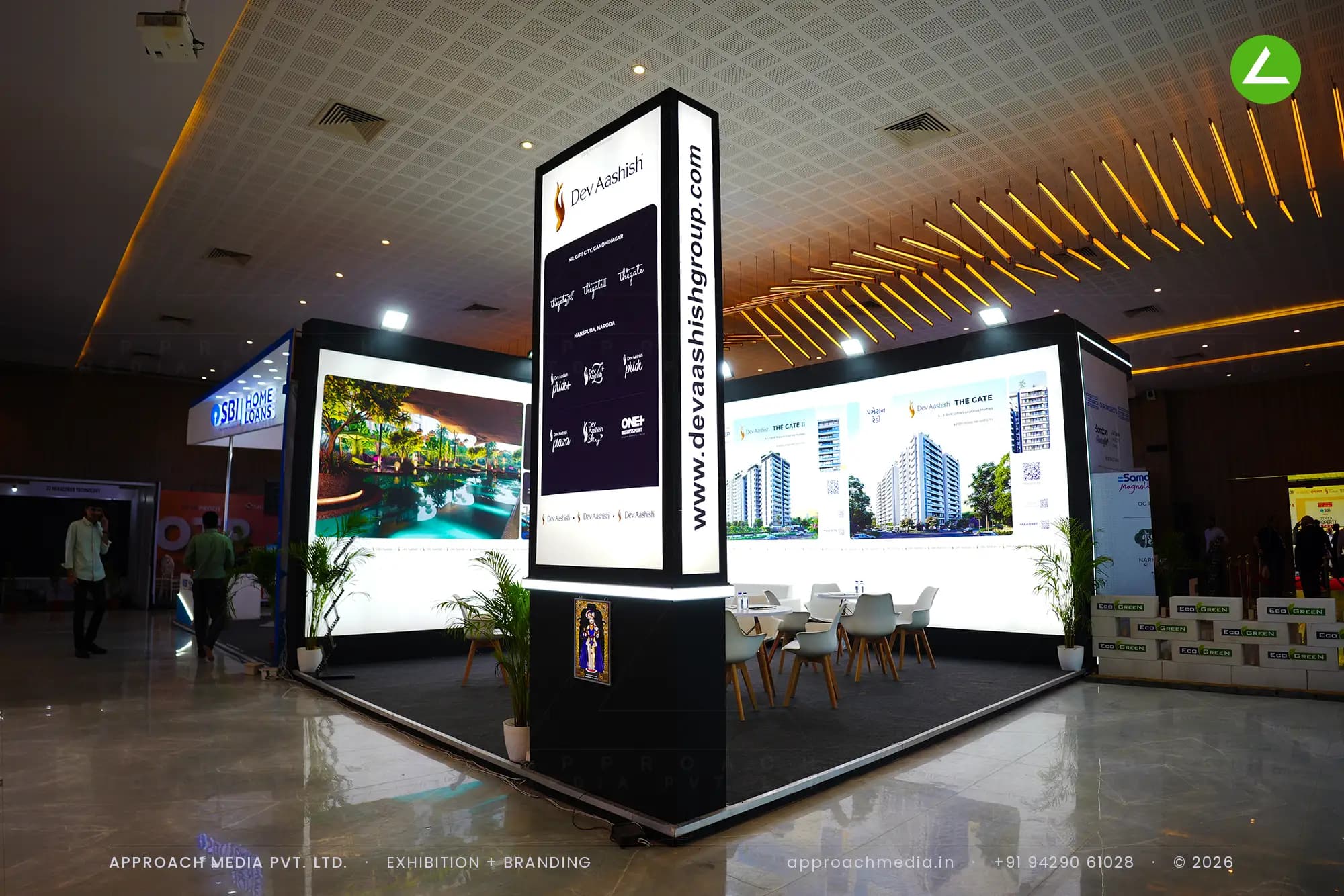 Dev Aashish Group exhibition stall design at Times Property Expo Ahmedabad with backlit fabric walls and a lit corner totem