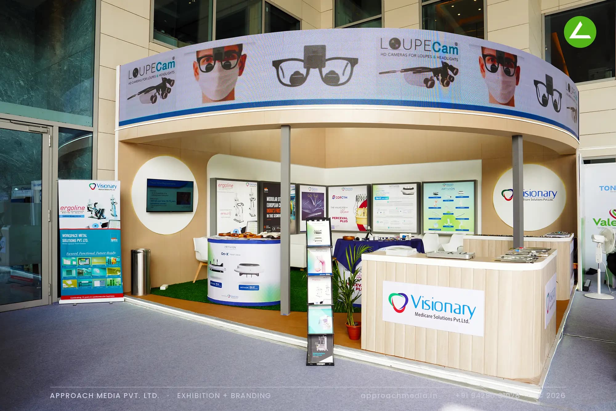 Curved fascia and oak walls in the exhibition stall design at CABG Gandhinagar for Visionary, with turf floor and lit panels